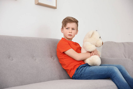 小孤独症男孩坐在沙发与玩具在家里