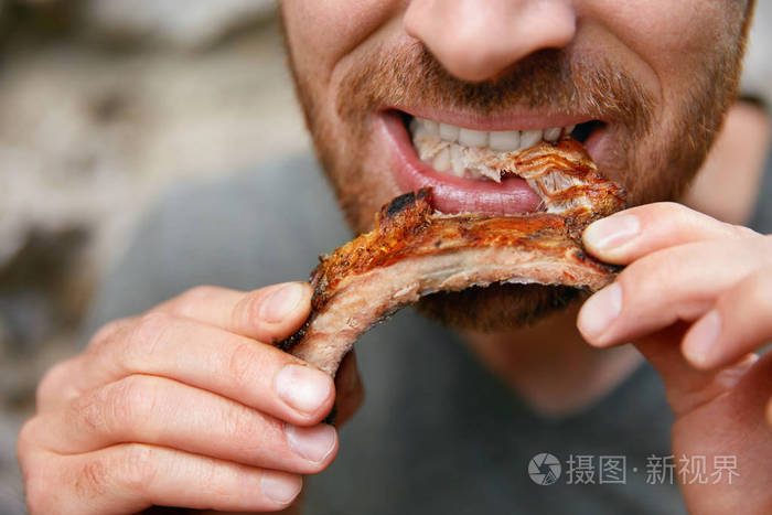 人吃烤肉肋骨在烧烤酒吧特写.男士在牛排屋里吃排骨.高分辨率