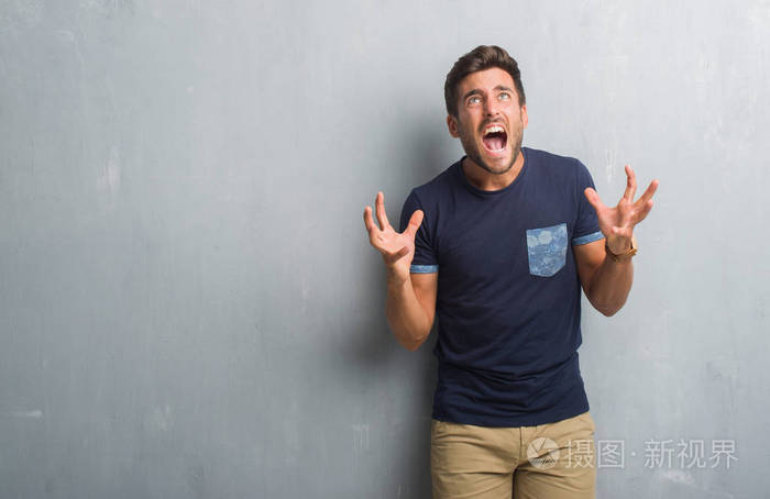 的年轻人在灰色的垃圾墙疯狂和疯狂的呼喊和激烈的表达和武器大声喊叫