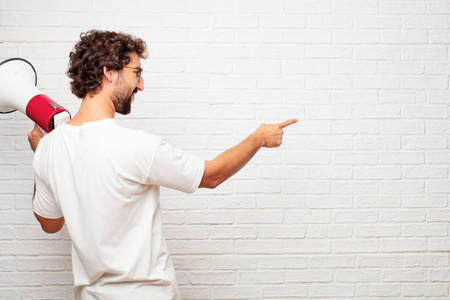 年轻的哑人回头看, 手放在臀部, 指着其他的手在远处的物体, 遥远的