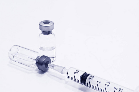 药瓶的药物或疫苗和3毫升塑料注射器与针隔离在白色背景, 蓝色色调颜色