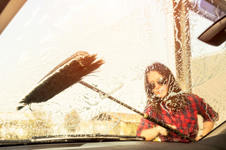 里面的漂亮的女人在洗玻璃通过视图解放概念与年轻女子洗车专注于画笔温暖葡萄酒过滤的期待与增强的 sunflare 晕
