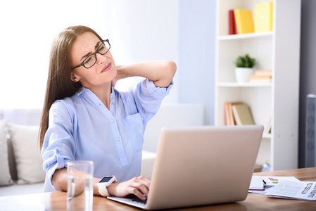 总是在触摸疲惫的女人在桌子旁工作照片