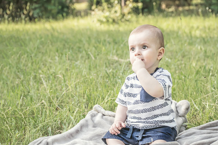 可爱的宝贝男孩大美丽的眼睛，坐在户外对自然的草地上