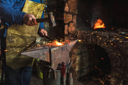 铁匠手工锻造熔融金属在铁匠的铁砧与火花烟花, 特写