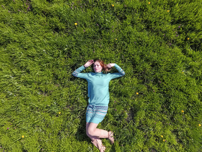 那女孩躺在草坪上的一条绿松石裙上。美丽的女孩躺在草地上
