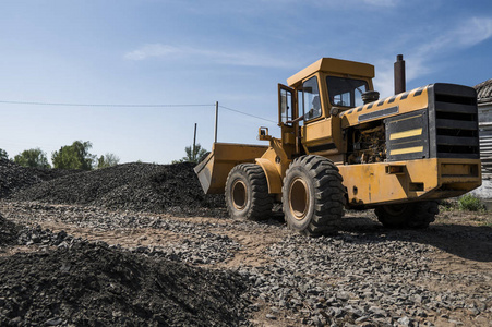 在公路建设工程中, 黄色装载机与碎石一起移动。道路上的石头。卸石