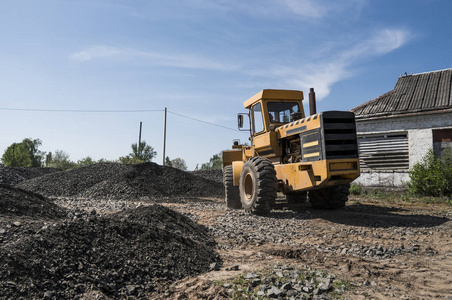 在公路建设工程中, 黄色装载机与碎石一起移动。道路上的石头。卸石