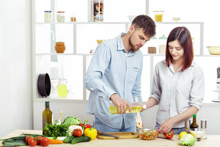 爱幸福的夫妇准备健康新鲜的蔬菜沙拉在厨房