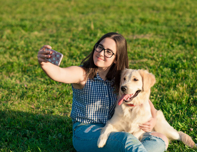 年轻女子和她友好的狗在公园拍拍照