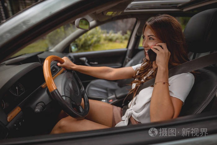 女人在开车时谈论智能手机的侧面观点