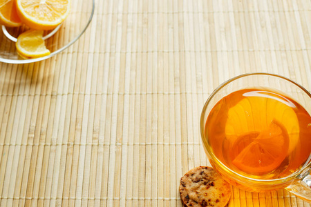 玻璃杯茶，饼干和柠檬轻木背景上。杯茶，柠檬和饼干。