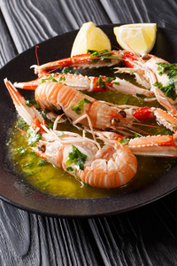 美味的煮 scampi 或小龙虾或挪威龙虾特写在一个盘子上的酱油和柠檬在桌子上。vertica