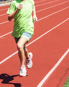 一个年轻的女孩穿着绿色的衬衫, 而运行在一个红色的轨道上
