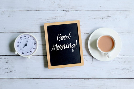 表钟上图, 一杯咖啡和黑板, 上面写着 早上好 的白色木质背景