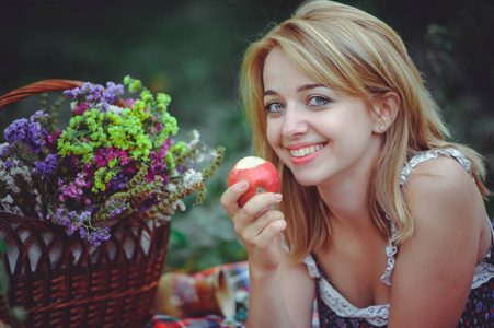 年轻女人说谎与苹果在野餐会上，健康的生活方式，幸福