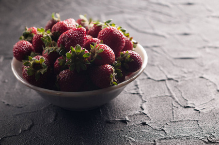 黑色背景的盘子里的新鲜草莓
