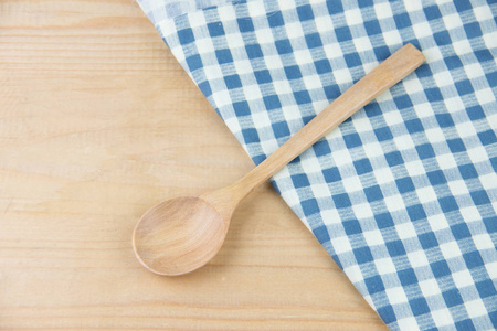 餐巾上的木勺蓝色和白色的格子在木桌上