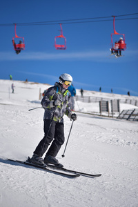 年轻男子滑雪与蓝蓝的天空和背景中的升降椅