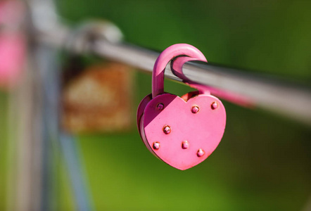闭合的粉红色心形挂锁。永恒的爱的象征。婚礼当天情人的传统。选择性聚焦