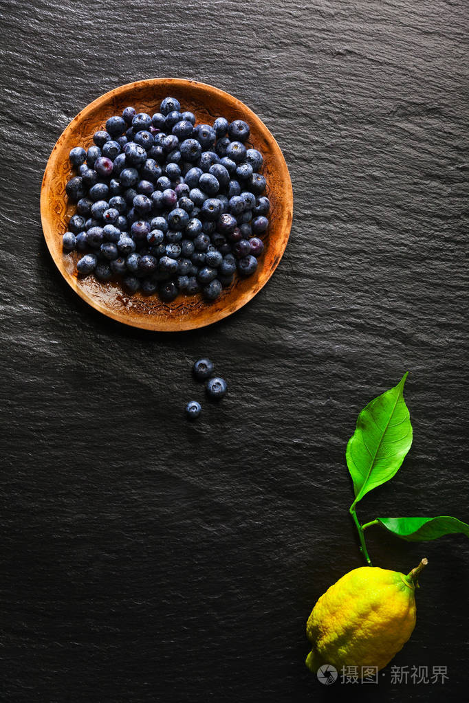 堆的蓝莓对黑色石背景和 l 板