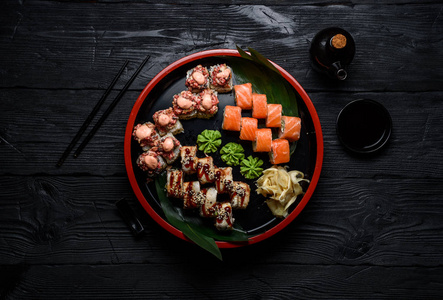 日本料理。在黑暗的木制背景设置在一个圆盘上的寿司