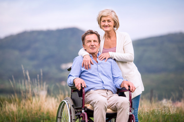 老人推着男人坐轮椅,绿色的天
