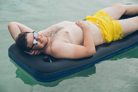 男子在海上的床垫上游泳。夏季时间概念