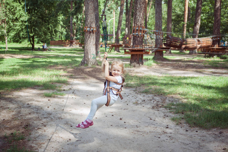 休闲活动。在一个极端的绳索公园里, 一个在马枪上的小女孩穿过绳子。