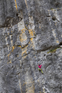 坚强的女孩爬上岩石，做运动攀登的性质