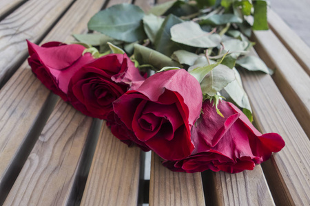 一束红玫瑰躺在木凳上