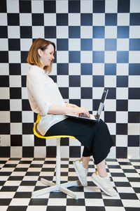 博客概念, 椅子上有笔记本电脑的女人。漂亮的女性自由职业者张贴通过互联网