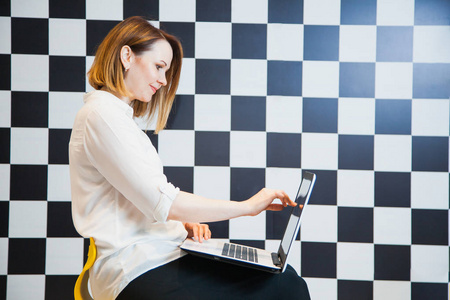 博客概念, 椅子上有笔记本电脑的女人。漂亮的女性自由职业者张贴通过互联网