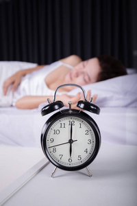 时钟显示 6 上午和睡在床上的女人