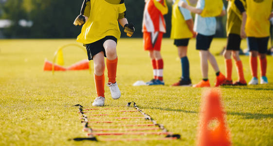 年轻运动员训练与橄榄球设备。孩子们的足球速度训练。青年足球运动员在蓝色运动装在训练会议在草足球场