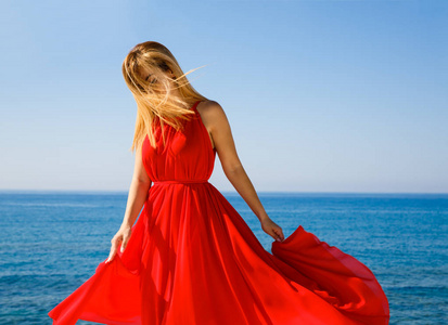 在塞浦路斯海滩的红色礼服漂亮的金发女郎