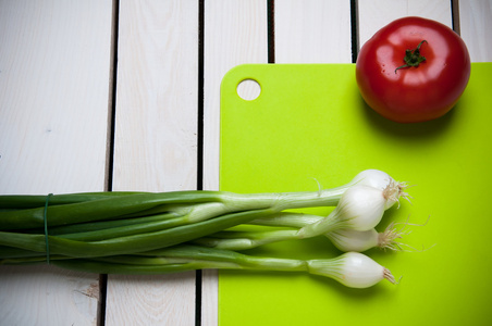 绿色切削板，木制的白色背景上的蔬菜