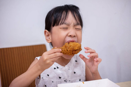 亚洲的中国小女孩在室内餐厅吃炸鸡照片