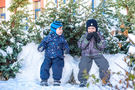 两个小家伙男孩在颜色鲜艳的衣服在降雪期间在户外玩.