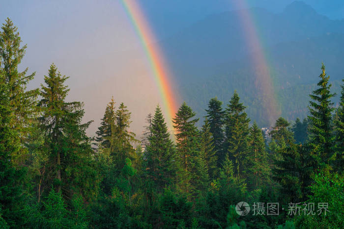 一个美丽的自然现象, 两个彩虹的背景下, 山覆盖着森林后雨