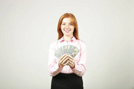 年轻漂亮的红发女人的肖像, 拿着一大把的钱持有100美元的栈像风扇.