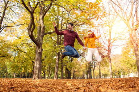 快乐的情侣在秋天的公园里跳着微笑