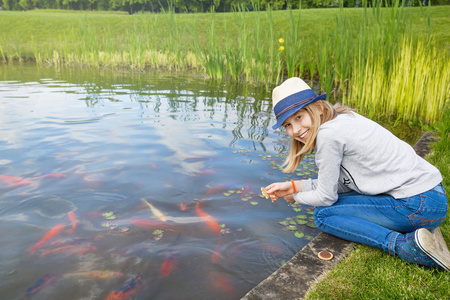 女孩少年饲养在一个池塘里的鱼