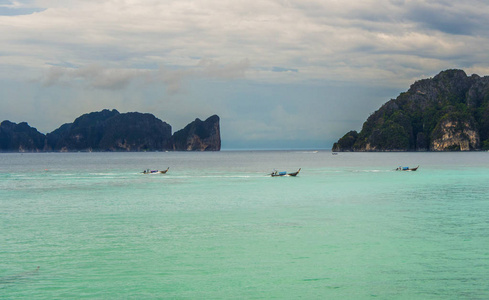 安达曼海的岩石岛屿。三条长尾船在绿松石水与山背景