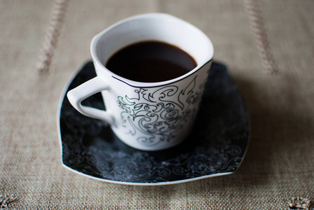 黑咖啡在老式杯子在纺织品背景