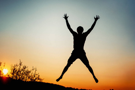 快乐的人在日落时跳跃着欢乐。成功与幸福理念