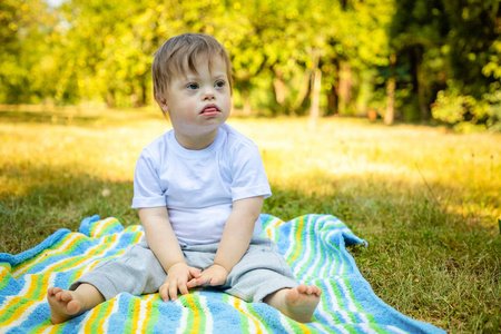 可爱小男孩的肖像在夏天的毯子上玩耍的唐氏综合症