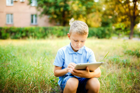 和平精英游戏年轻的孩子坐在院子里和平板电脑上玩游戏照片
