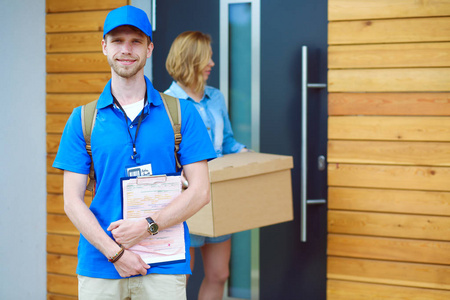蓝色制服包裹盒送交收件人信使服务概念的交付男人微笑着。穿蓝色制服的男人微笑着交货