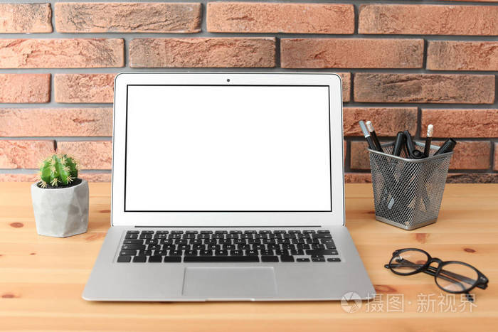 现代笔记本电脑在桌子上反对砖墙。用空格模拟文本